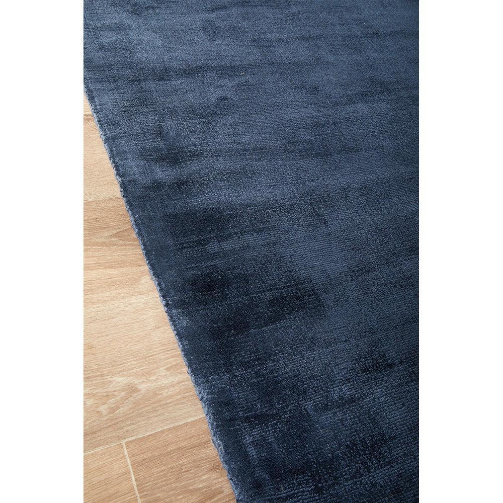 Joy Denim Rug featuring solid denim texture in deep navy and indigo on warm wood floor, hand-tufted wool