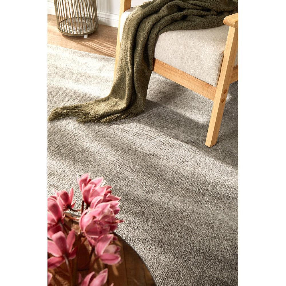 Joy Grey Rug featuring subtle textured weave in charcoal, mid-grey and light grey on warm beige floor, hand-tufted wool