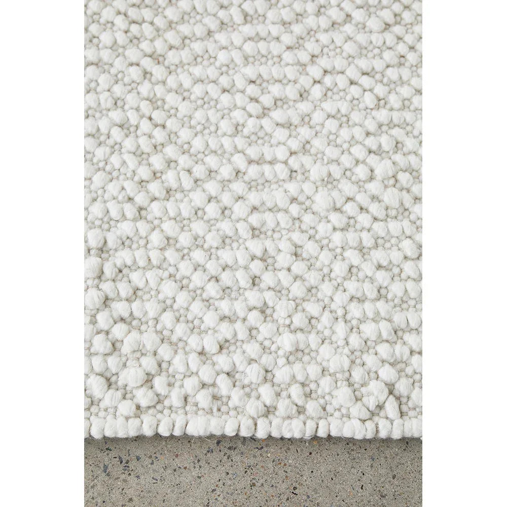 Boucle White Rug featuring chunky boucle texture in ivory/cream on light grey concrete floor, hand-tufted wool