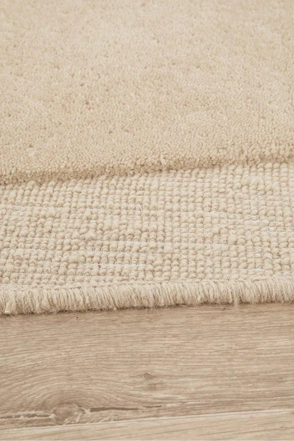 Cleo Beige Rug featuring soft curved abstract pattern in beige, cream and ivory on light wood background, hand-tufted wool