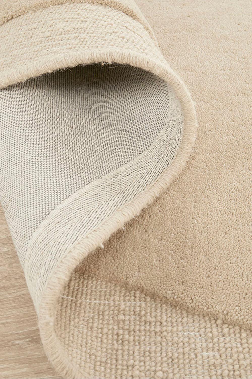 Cleo Beige Rug featuring soft textured solid design in cream, beige and taupe on warm light wood backdrop, power-loomed wool blend