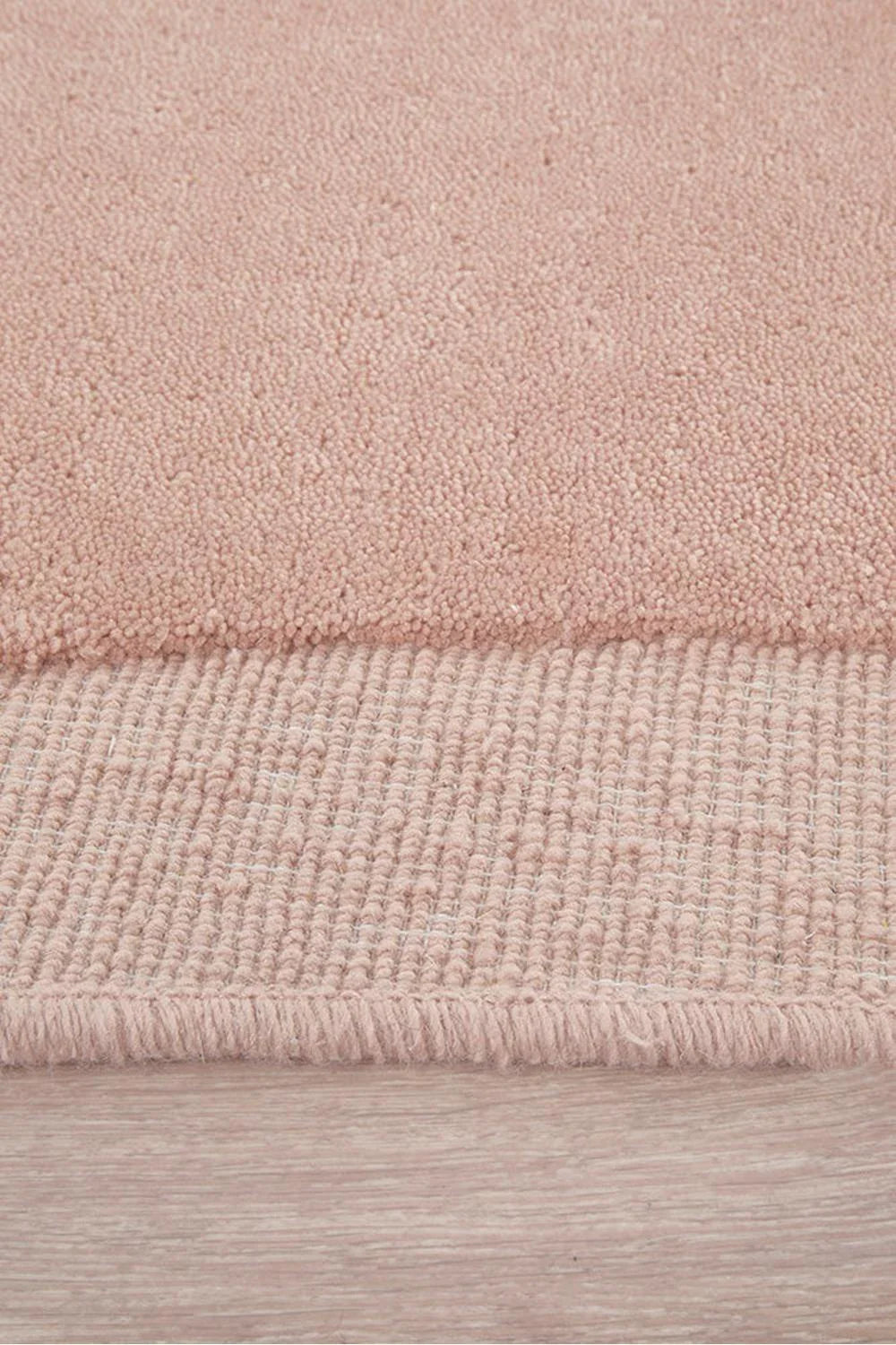Cleo Blush Rug featuring solid shaggy texture in blush pink, rose pink and dusty pink on pale wood background, hand-tufted wool
