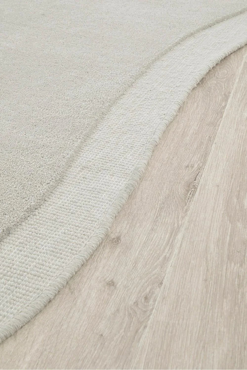 Cleo Dove Rug featuring soft curved edge design in ivory, cream, beige and taupe on light oak floor, hand-tufted wool