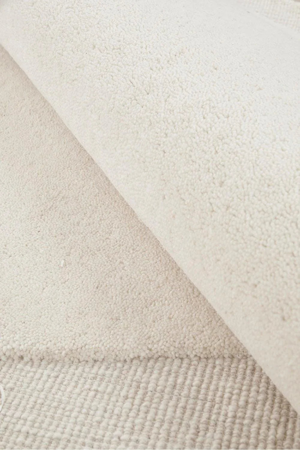 Cleo Milk Rug featuring soft curved abstract pattern in ivory, cream and taupe on warm beige background, hand-tufted wool