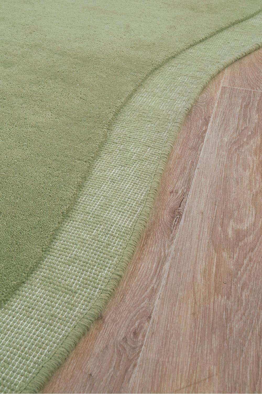 Cleo Moss Rug featuring solid moss green with a woven border on warm oak floor, machine-made polypropylene
