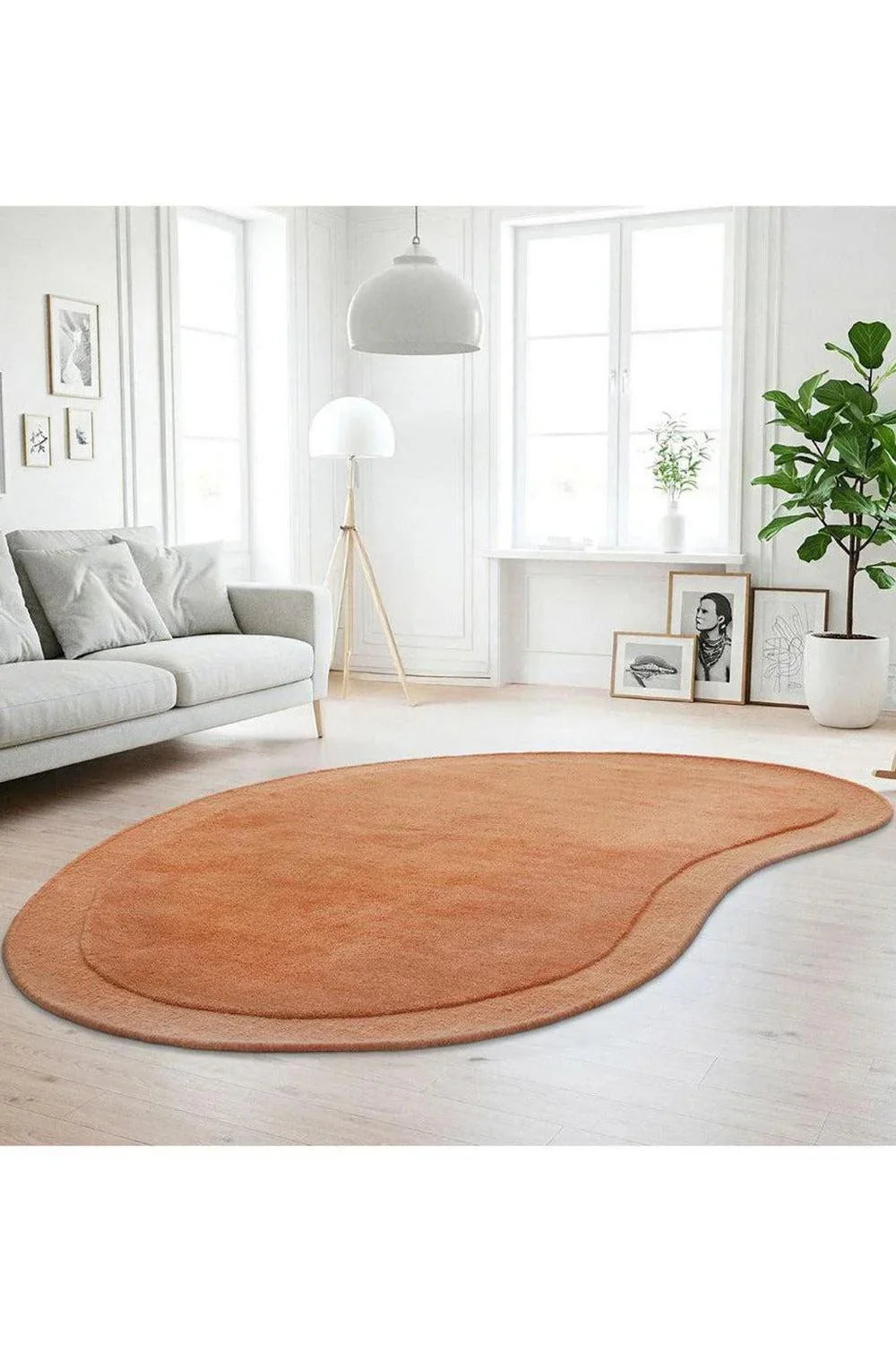 Cleo Rug featuring abstract curved shape in burnt orange, peach and coral on pale wood floor, machine-woven synthetic blend