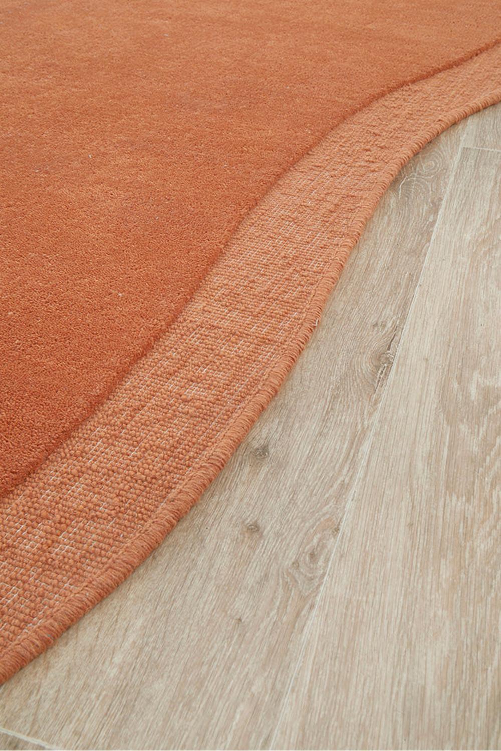 Cleo Spice Rug featuring solid orange curves in warm rust on pale oak background, hand-tufted wool