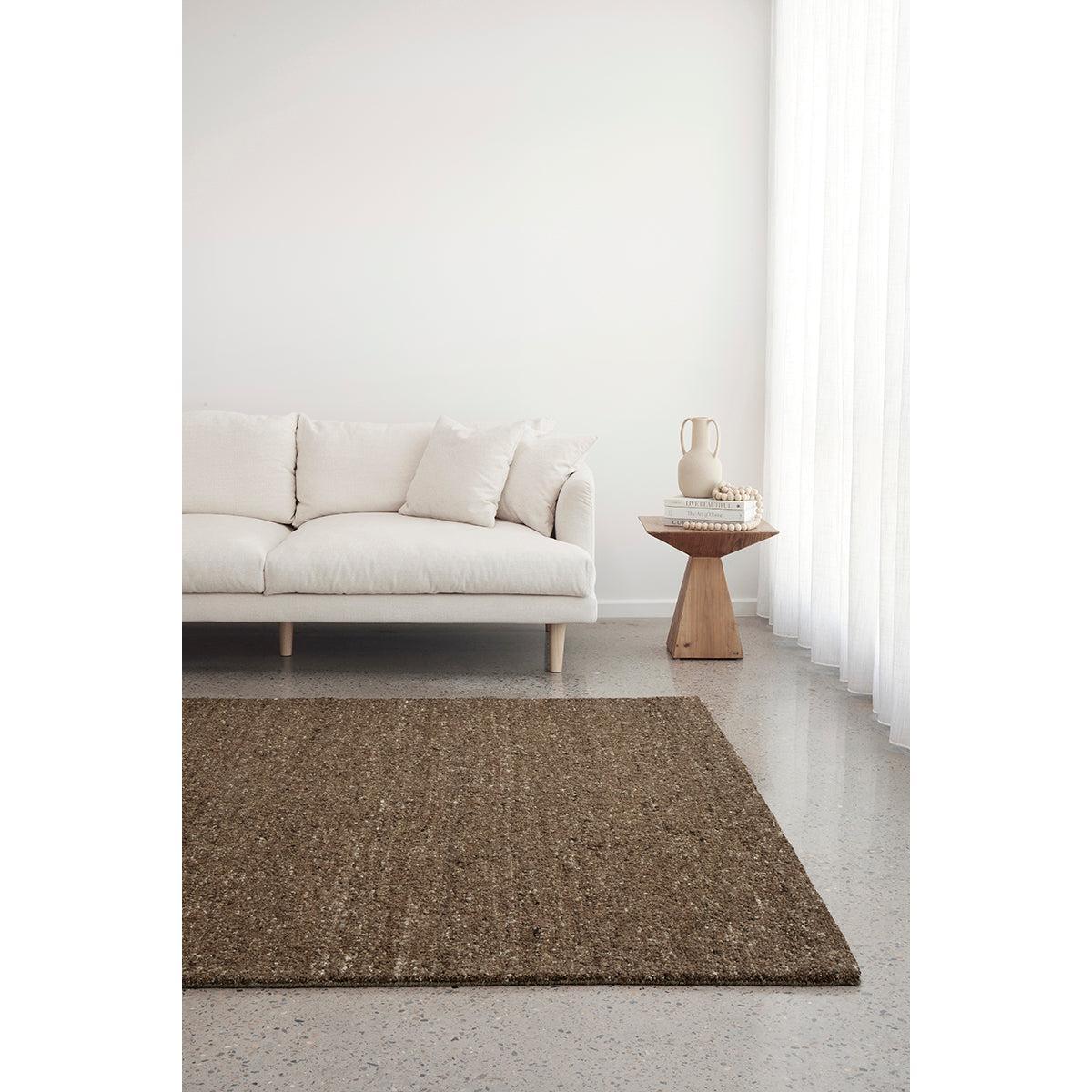 Conscious Loom Embrace Brown Rug featuring woven pattern in dark brown, tan and cream on grey floor, hand-woven jute