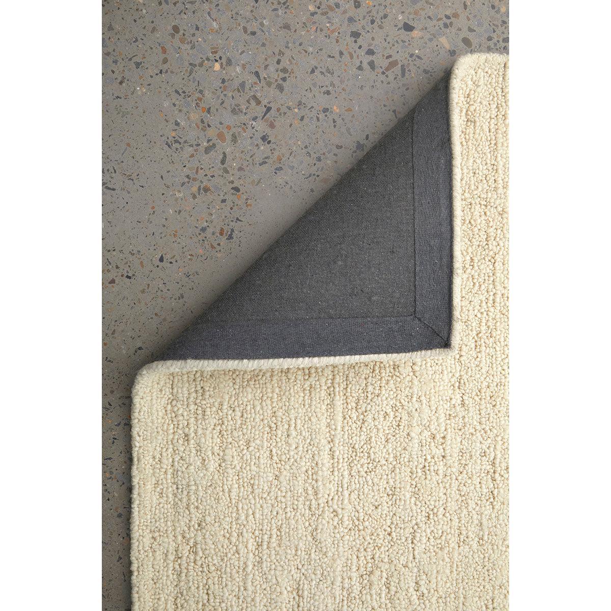 Conscious Loom Embrace Cream Rug featuring textured boucle in cream with charcoal underside on grey terrazzo background, loom-woven