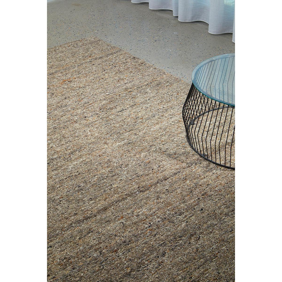 Conscious Loom Embrace Stone Rug featuring flecked pattern in sand, beige, taupe on grey concrete, hand-tufted wool