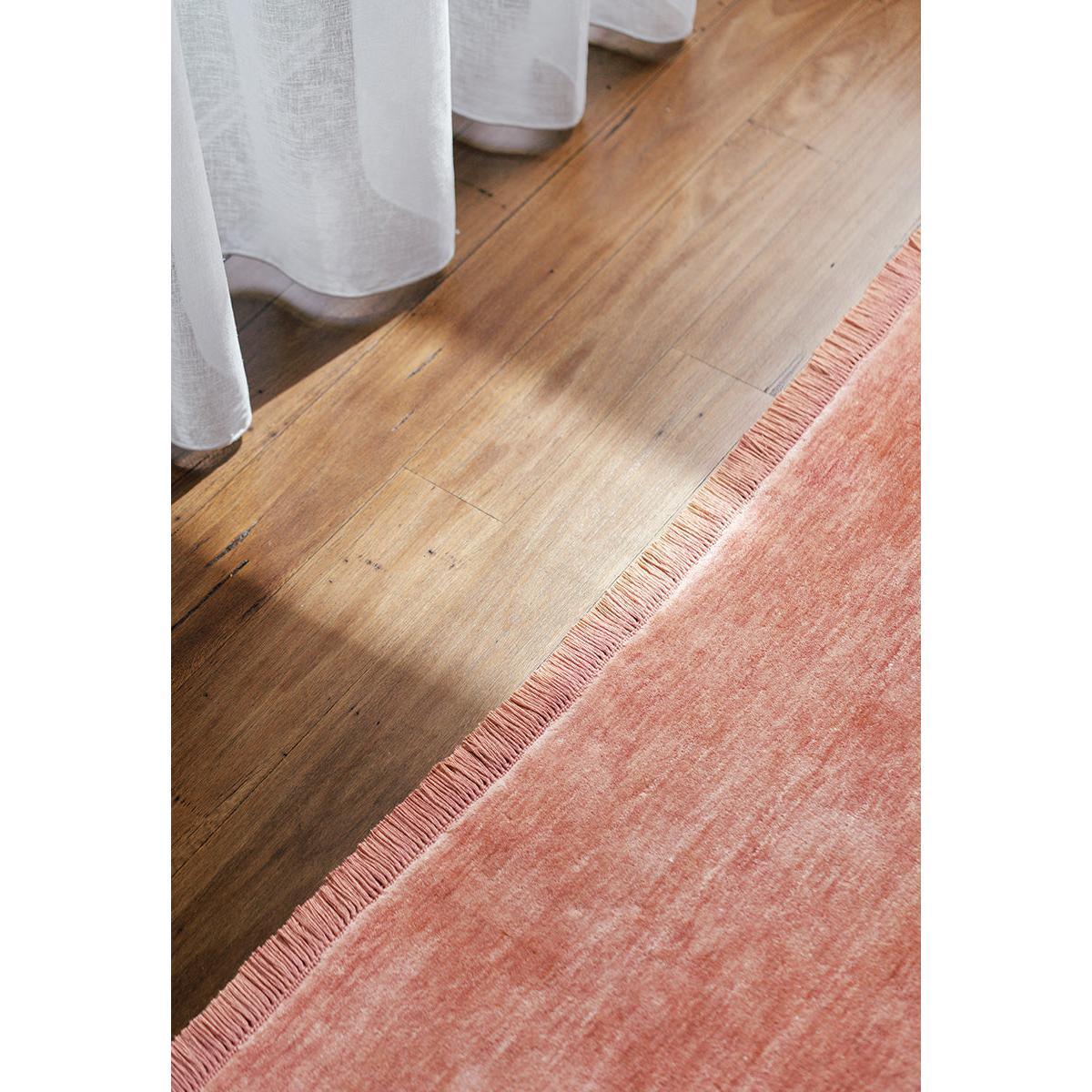 Conscious Loom Kinship Blush Pink Rug featuring solid blush pink with fringe on warm wood floor, hand-tufted wool