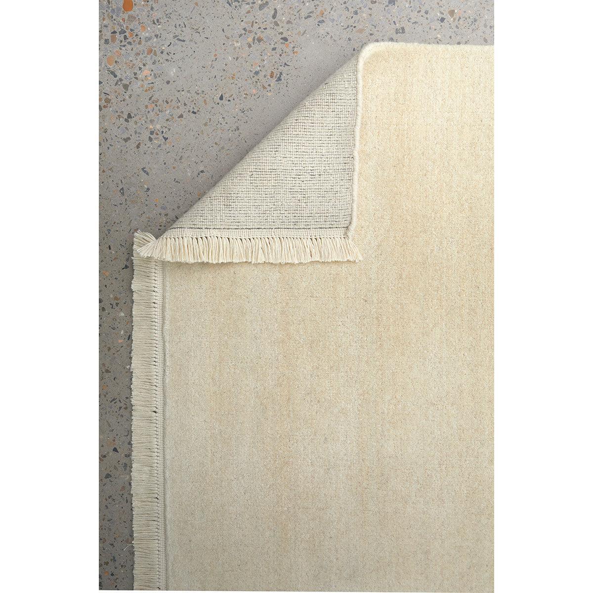Conscious Loom Kinship Cream Runner Rug featuring solid pattern in cream, beige and grey on grey terrazzo, loomed wool