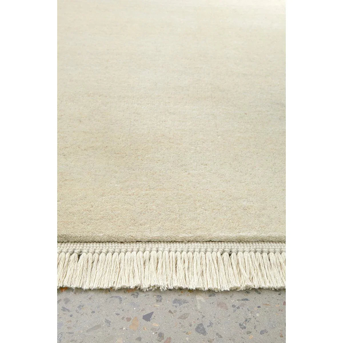 Conscious Loom Kinship Cream Rug featuring solid design in cream, ivory and beige on light grey floor, hand-loomed wool