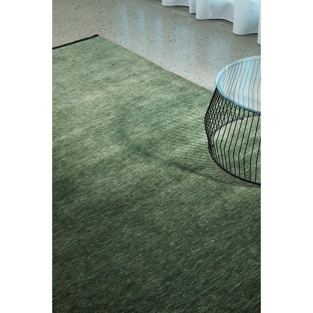 Conscious Loom Kinship Forest Green Rug featuring solid textured pattern in forest green, olive & sage on light grey background, loom-woven natural fibre