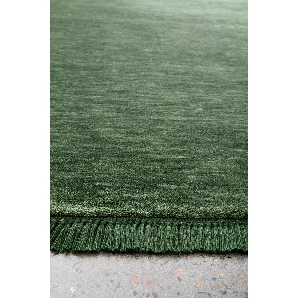 Conscious Loom Kinship Forest Green Rug featuring solid forest-to-olive pile on light grey background, loom-woven wool