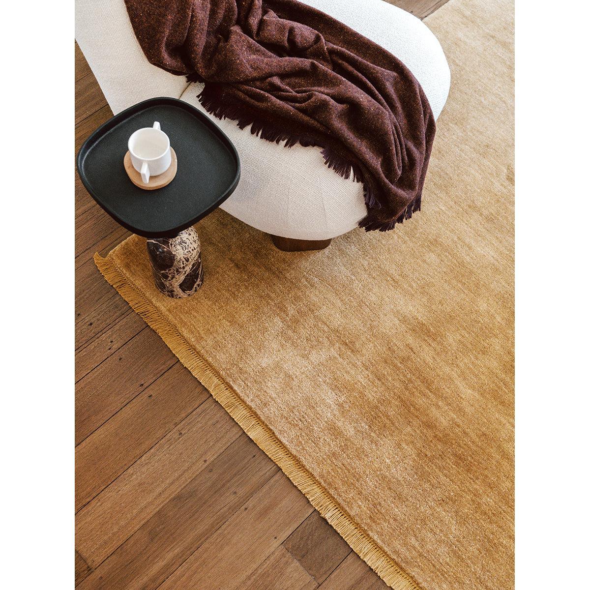 Conscious Loom Kinship Honey Rug featuring textured solid pattern in honey, cream and tan on warm wood, hand-loomed wool