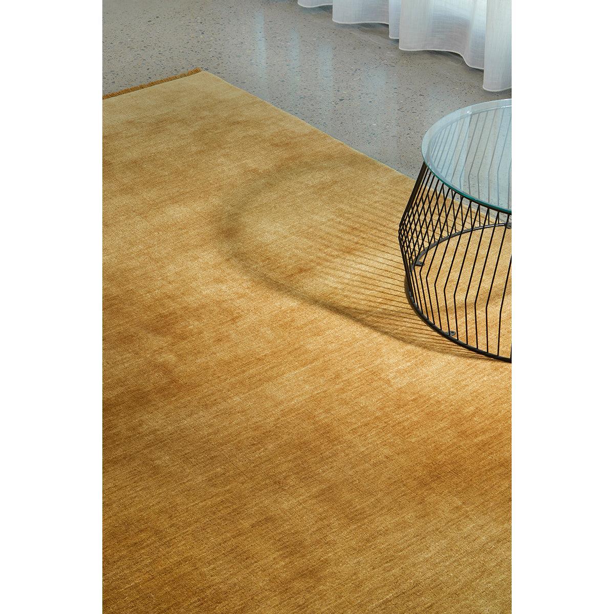 Conscious Loom Kinship Honey Rug featuring solid color in honey, amber, caramel on warm grey terrazzo, loom-woven wool