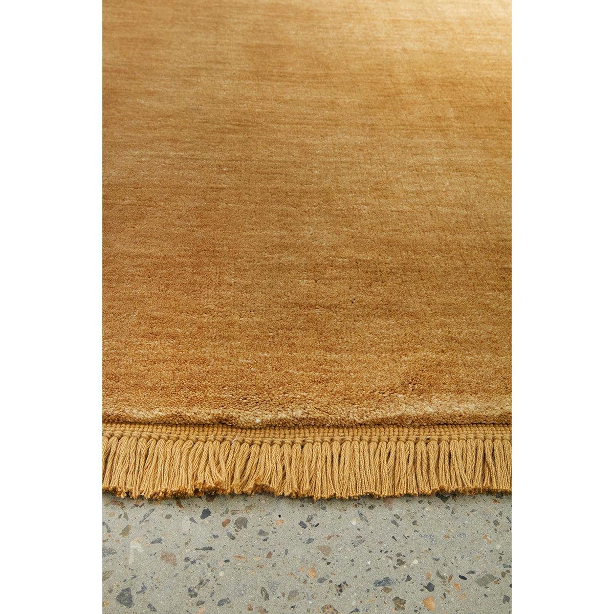 Conscious Loom Kinship Honey Rug featuring solid colour in honey, amber and ochre on light grey floor, hand-loomed wool
