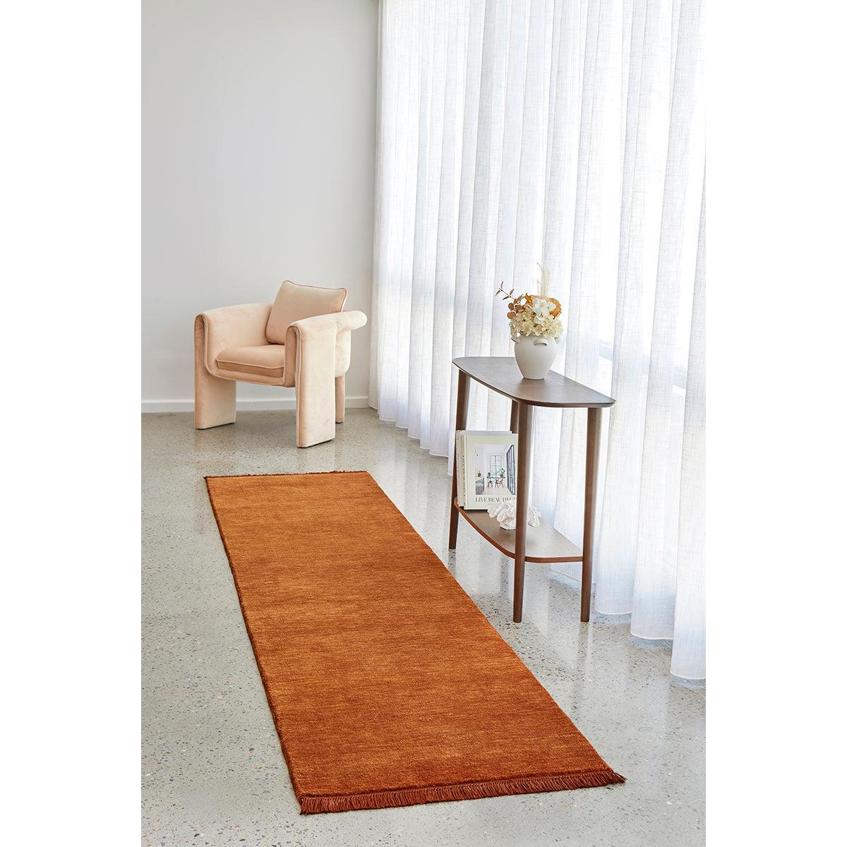 Conscious Loom Kinship Paprika Runner Rug featuring solid weave in paprika orange on pale beige floor, handwoven wool