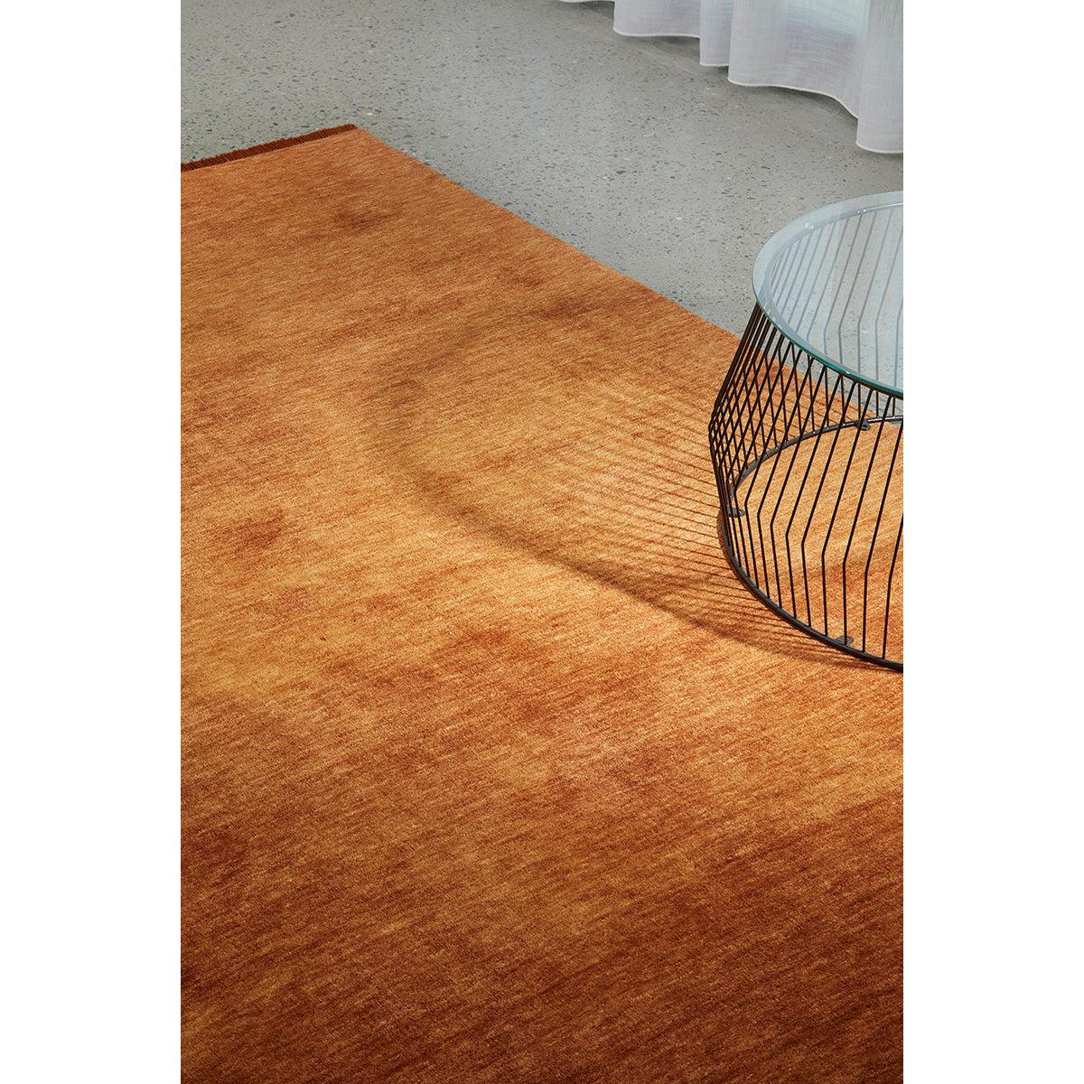 Conscious Loom Kinship Paprika Rug featuring paprika orange, copper and rust textures on grey floor, handwoven wool