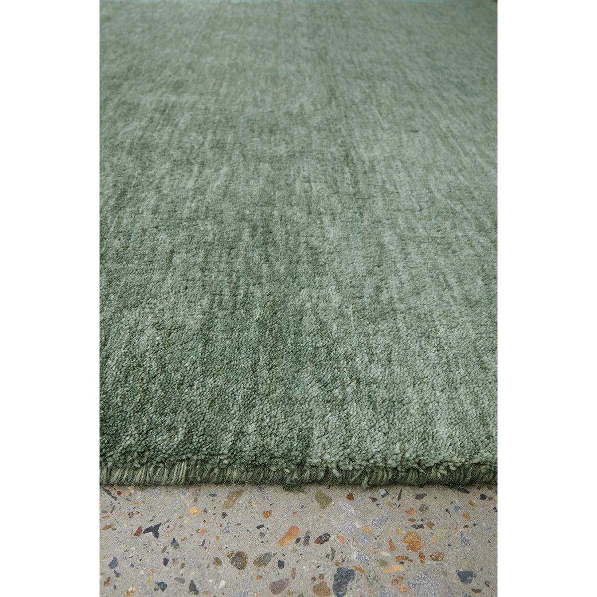 Conscious Loom Kinship Sage Green Rug featuring textured sage-green pile on light grey terrazzo floor, hand-tufted wool