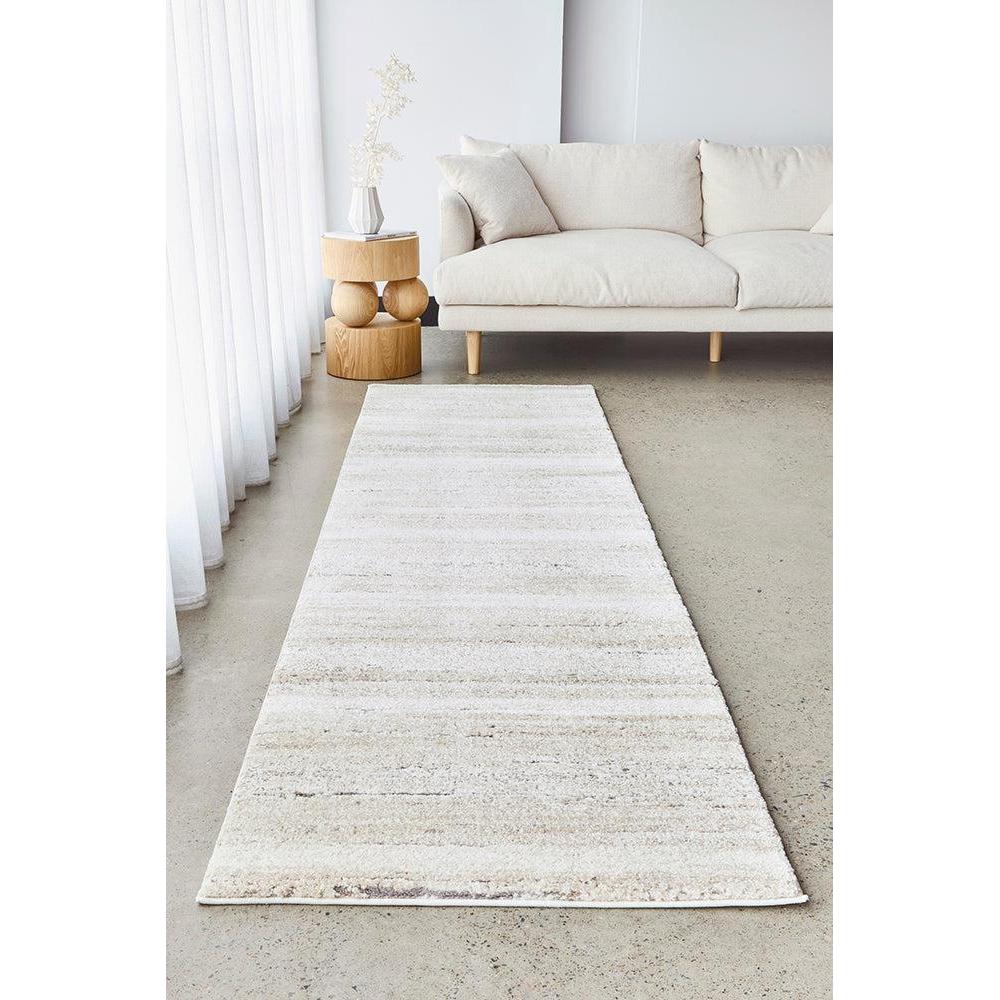 White runner rug on a light gray floor in a living room with a white sofa and decorative items.