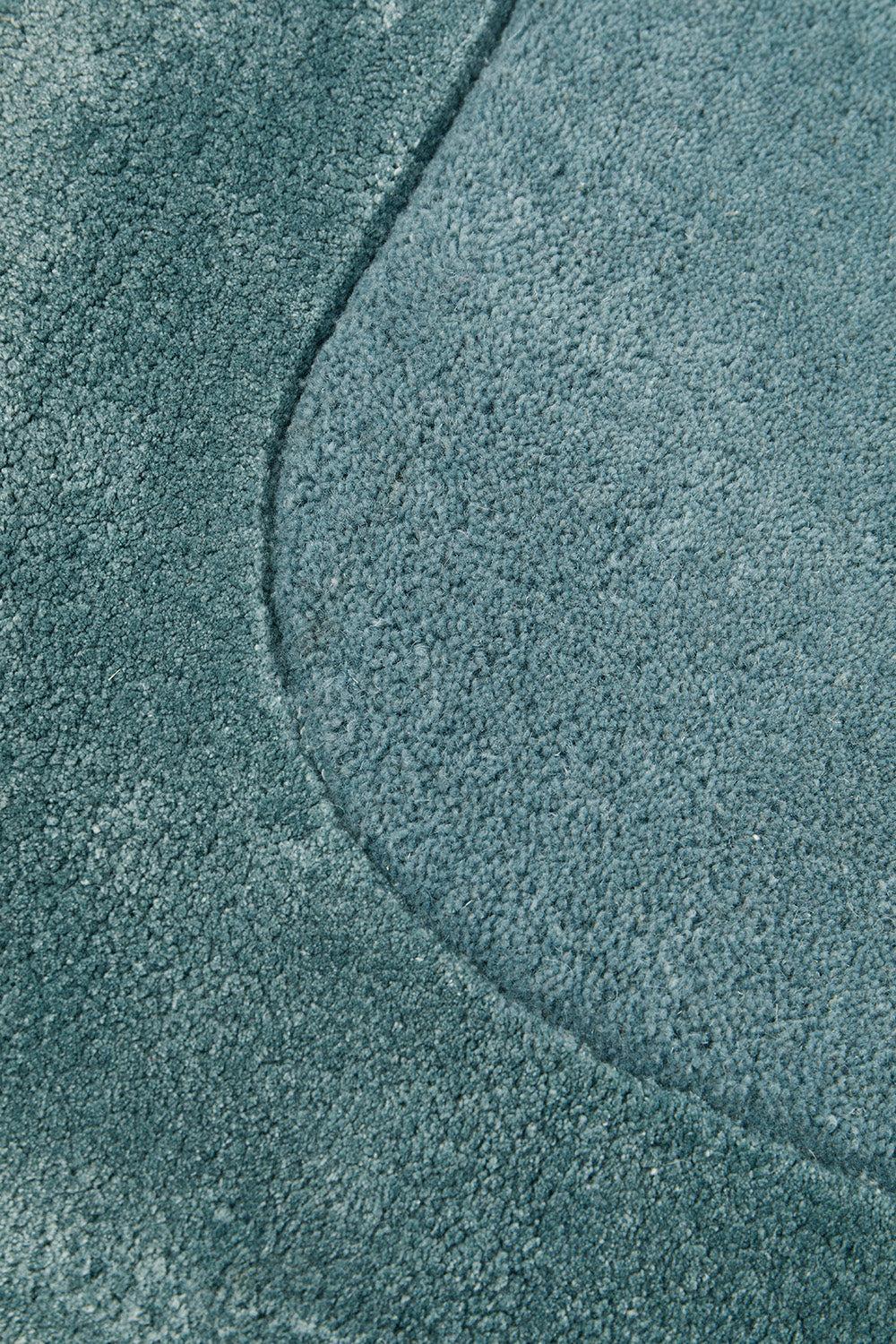 Hugo Blue Rug featuring textured solid pile in teal blue on blue background, by Rug Culture