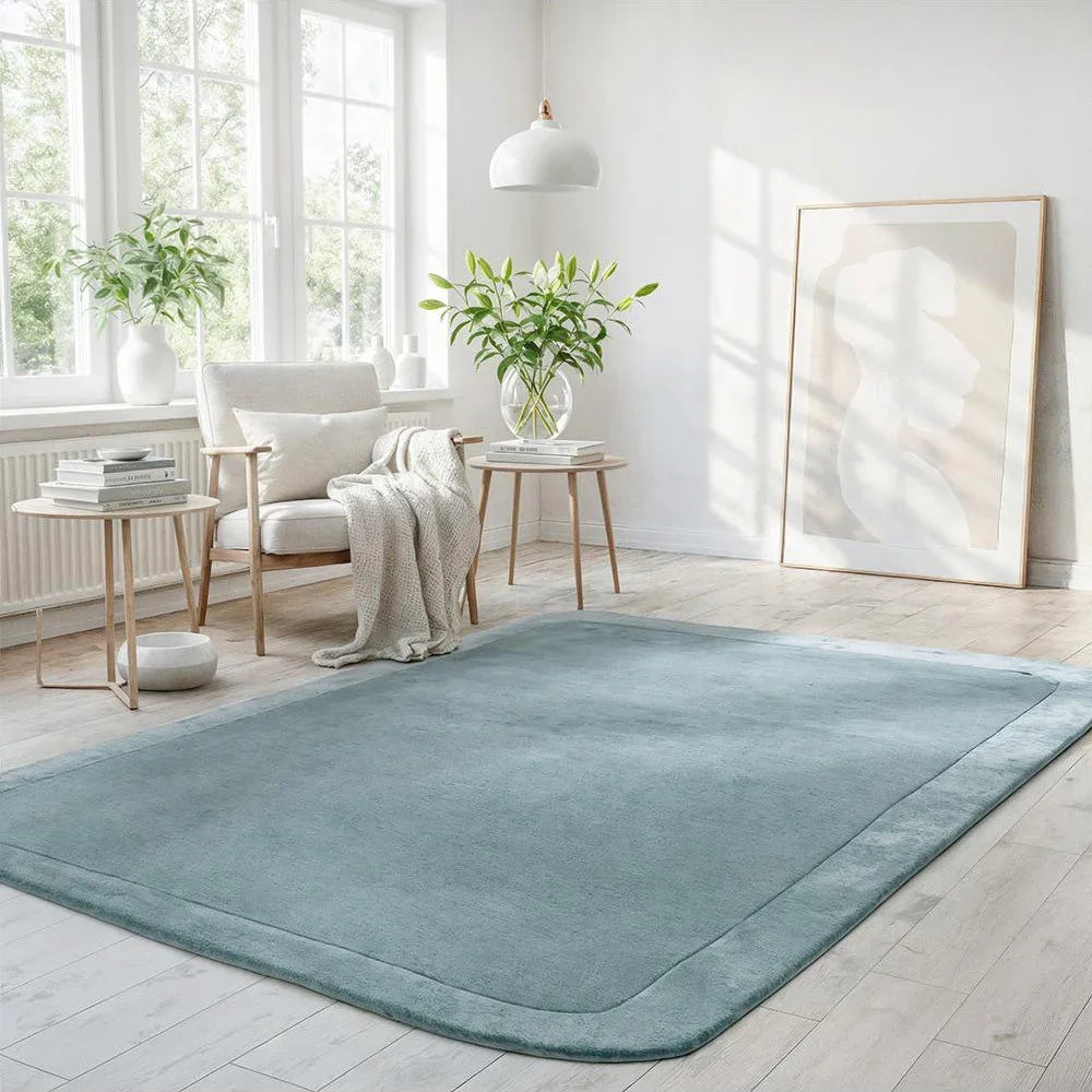 Hugo Blue Rug featuring solid minimalist design in teal blue on pale beige floor, hand-tufted wool