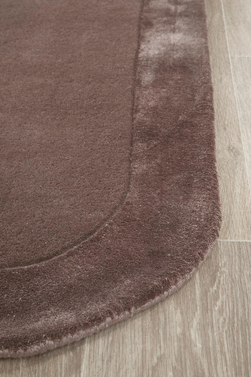 Hugo Grape Rug featuring solid design in chocolate brown with darker border on light wood floor, hand-tufted wool blend