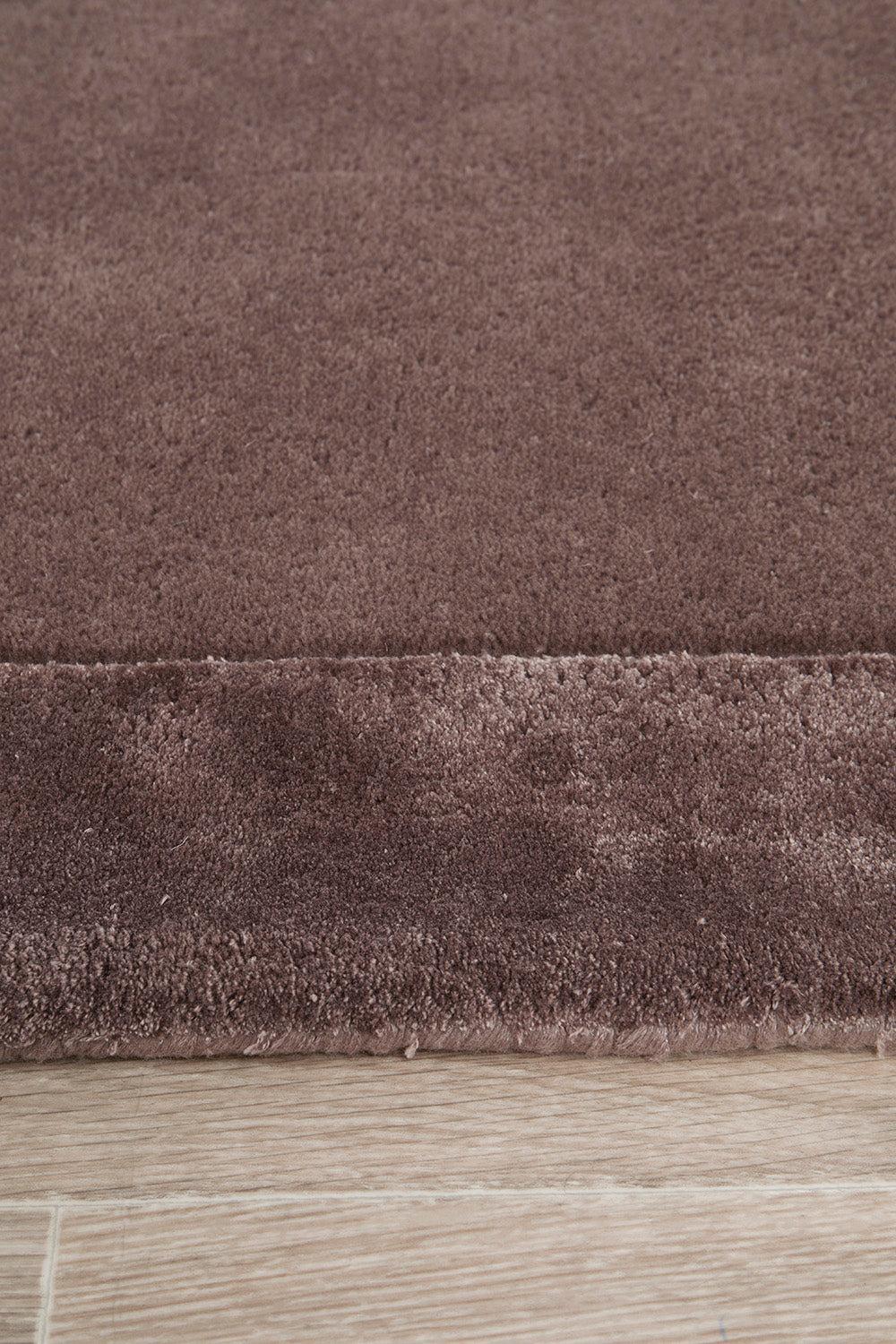 Hugo Rug featuring solid textured pattern in plum and brown on light oak background, hand-tufted wool