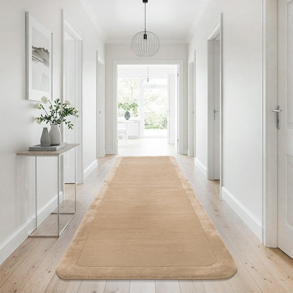 Beige rug on a wooden floor in a bright hallway with white walls and a glass side table.