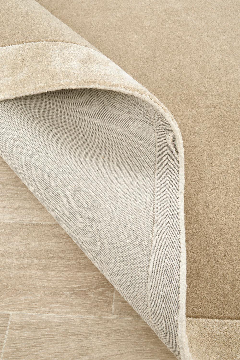 Hugo Husk Rug featuring solid minimalist design in warm tan, beige and ivory on light oak flooring, machine-woven wool