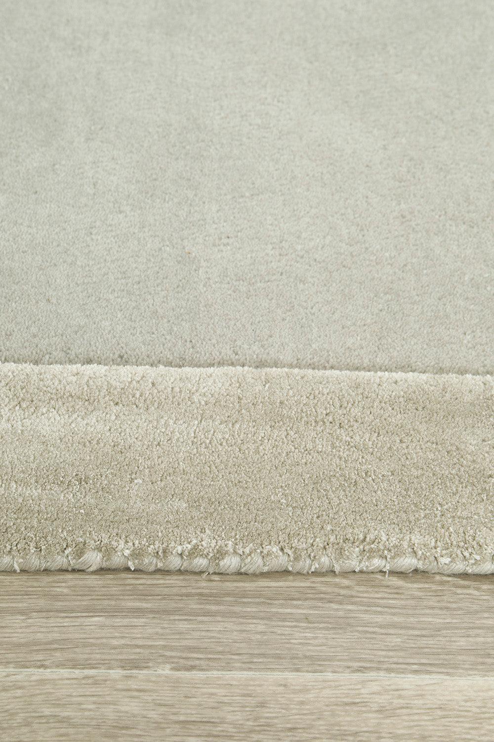 Hugo Silver Rug featuring solid textured pile in silver, cream and beige on light wood floor, hand-tufted wool
