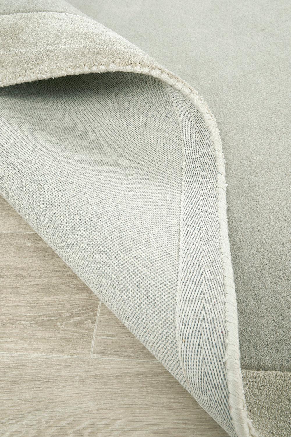 Hugo Silver Rug featuring woven texture with rolled edge in silver-grey and ivory on light beige background, hand-tufted wool