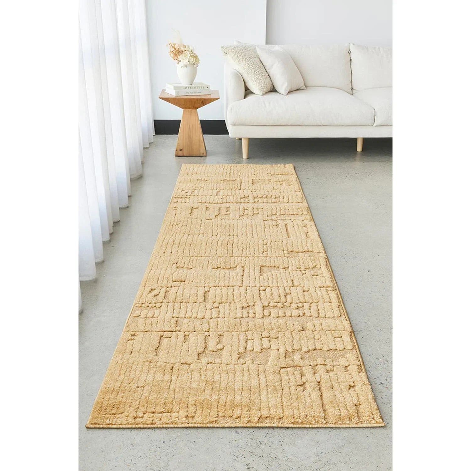 Beige textured runner rug in a living room setting with a white sofa and small table.