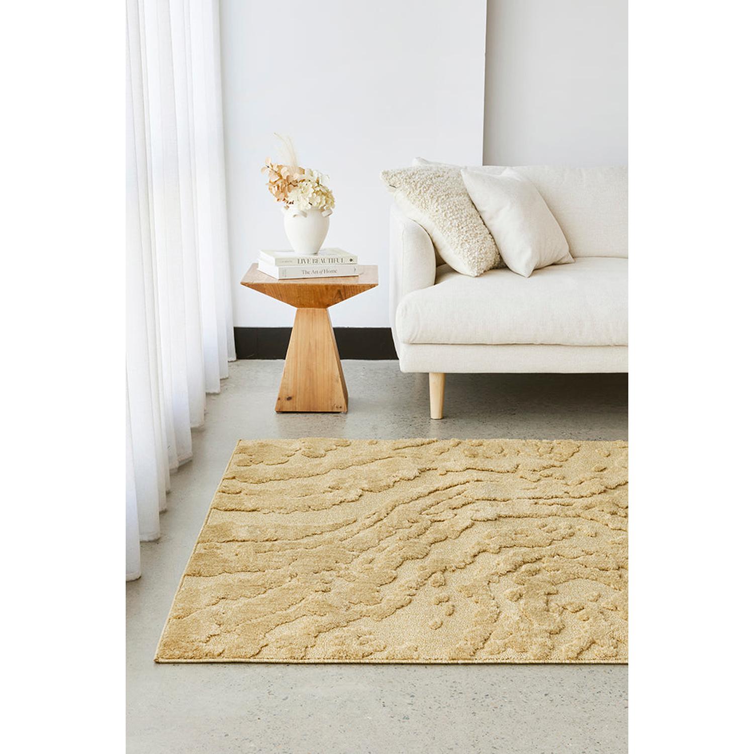 Beige textured rug in a living room with a white sofa and wooden side table.