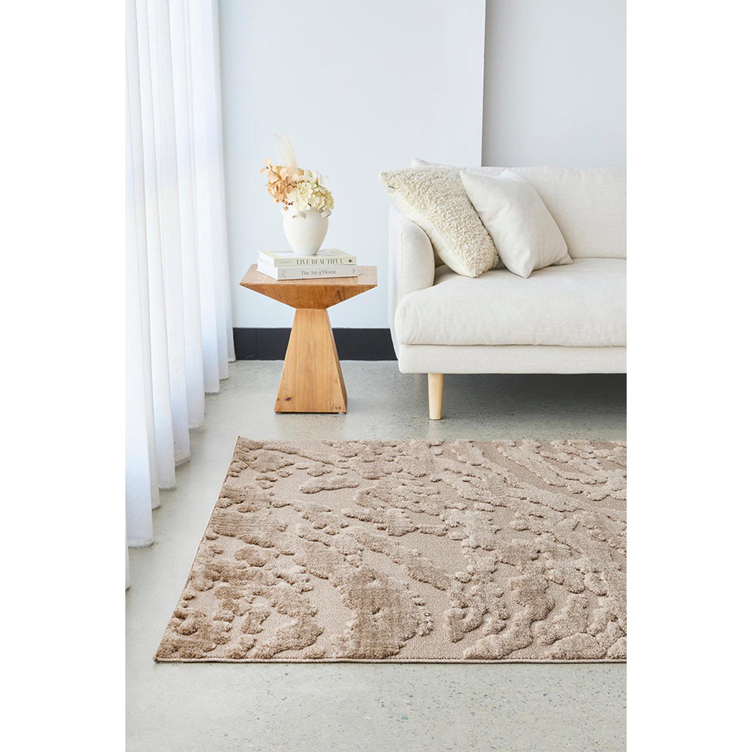Living room with a beige textured rug, white sofa, and wooden side table.