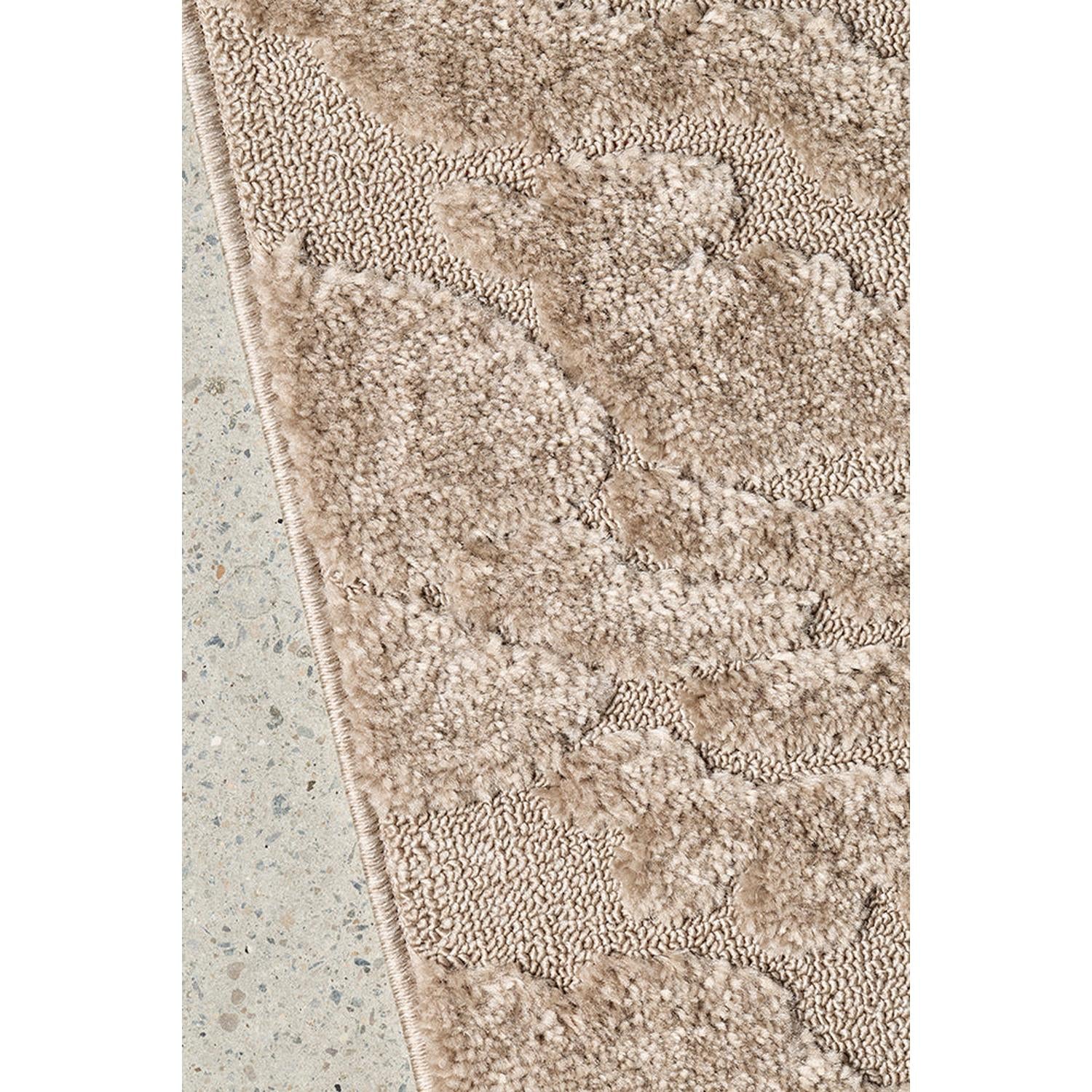Close-up of a textured beige rug on a concrete floor
