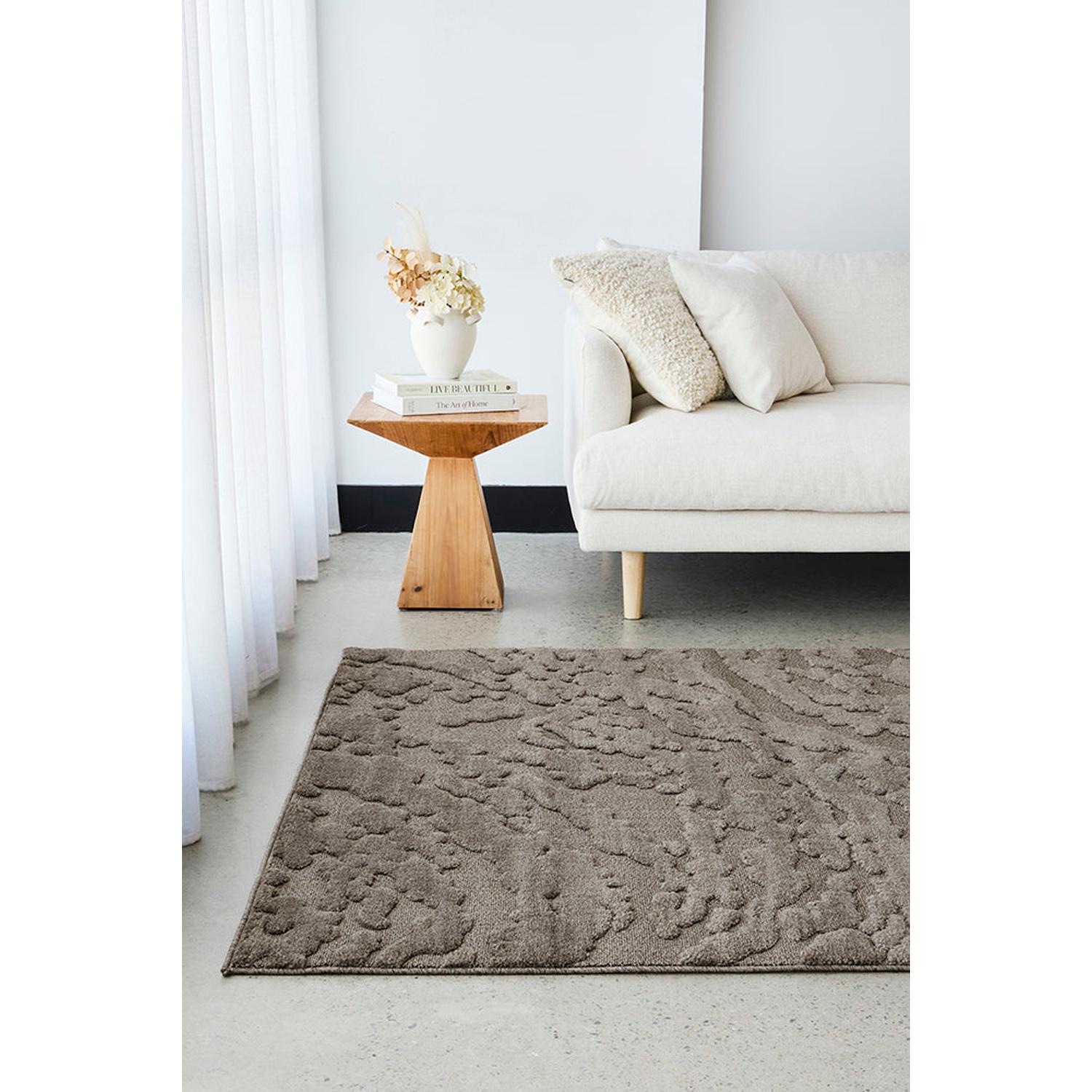 Living room with a textured gray rug, white sofa, and wooden side table.