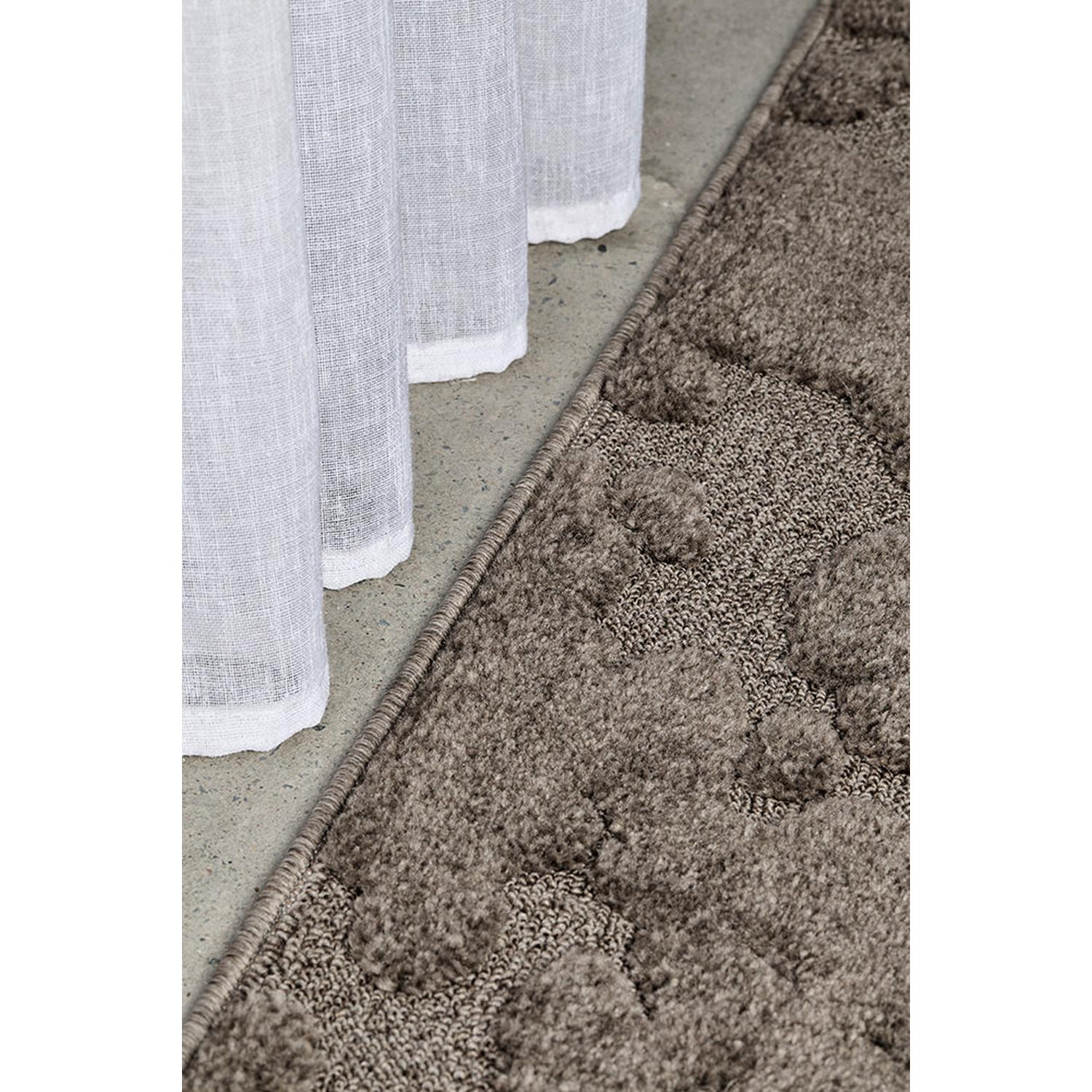 Close-up of a textured brown rug transitioning to a light gray floor.