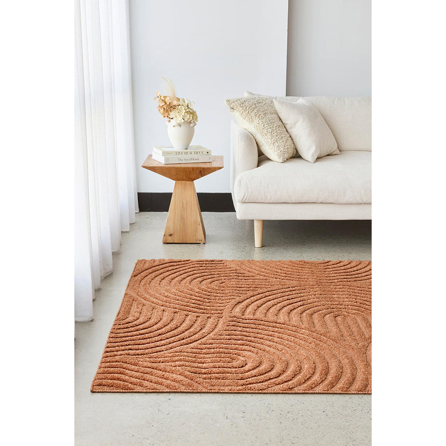 Living room with a textured brown rug, white sofa, and wooden side table.