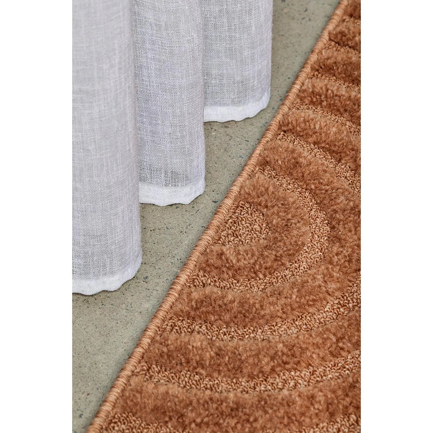 Haven Zina Rust Rug featuring textured wave motif in rust, copper and bronze on concrete grey background, hand-tufted wool