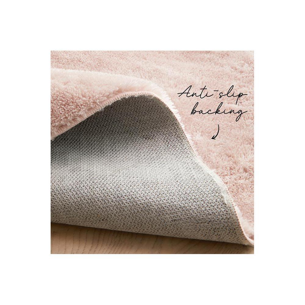 Jelly Bean Rose Rug featuring plush shag in blush pink with grey anti-slip backing on light wood floor, hand-tufted polyester