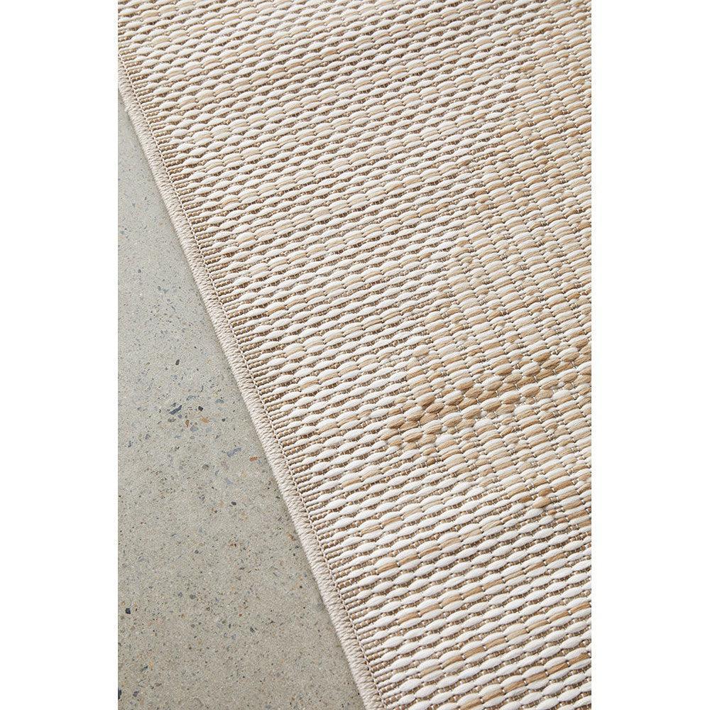 Patio Rico Natural Indoor-Outdoor Rug featuring woven textured pattern in beige, tan and cream on light concrete background, flat-weave natural fibre