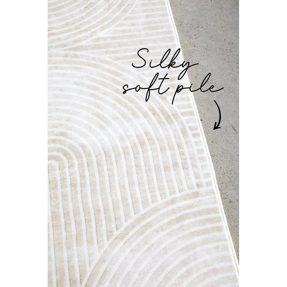 Revive Byron Natural Washable Rug featuring circular radiating pattern in ivory, cream and light beige on grey concrete, machine-made cotton