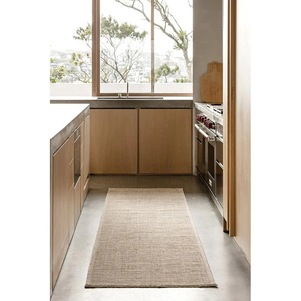 Steph And Gian Birch Flax Runner Rug featuring flatweave in beige, cream and taupe on grey concrete floor, handwoven flax