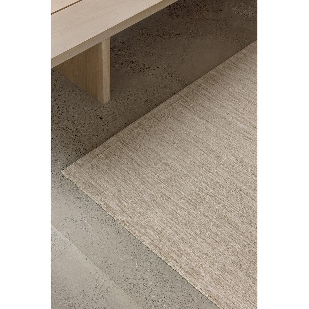 Steph And Gian Birch Flax Rug with understated textured weave in beige, cream, taupe on concrete grey background, hand-loomed flax