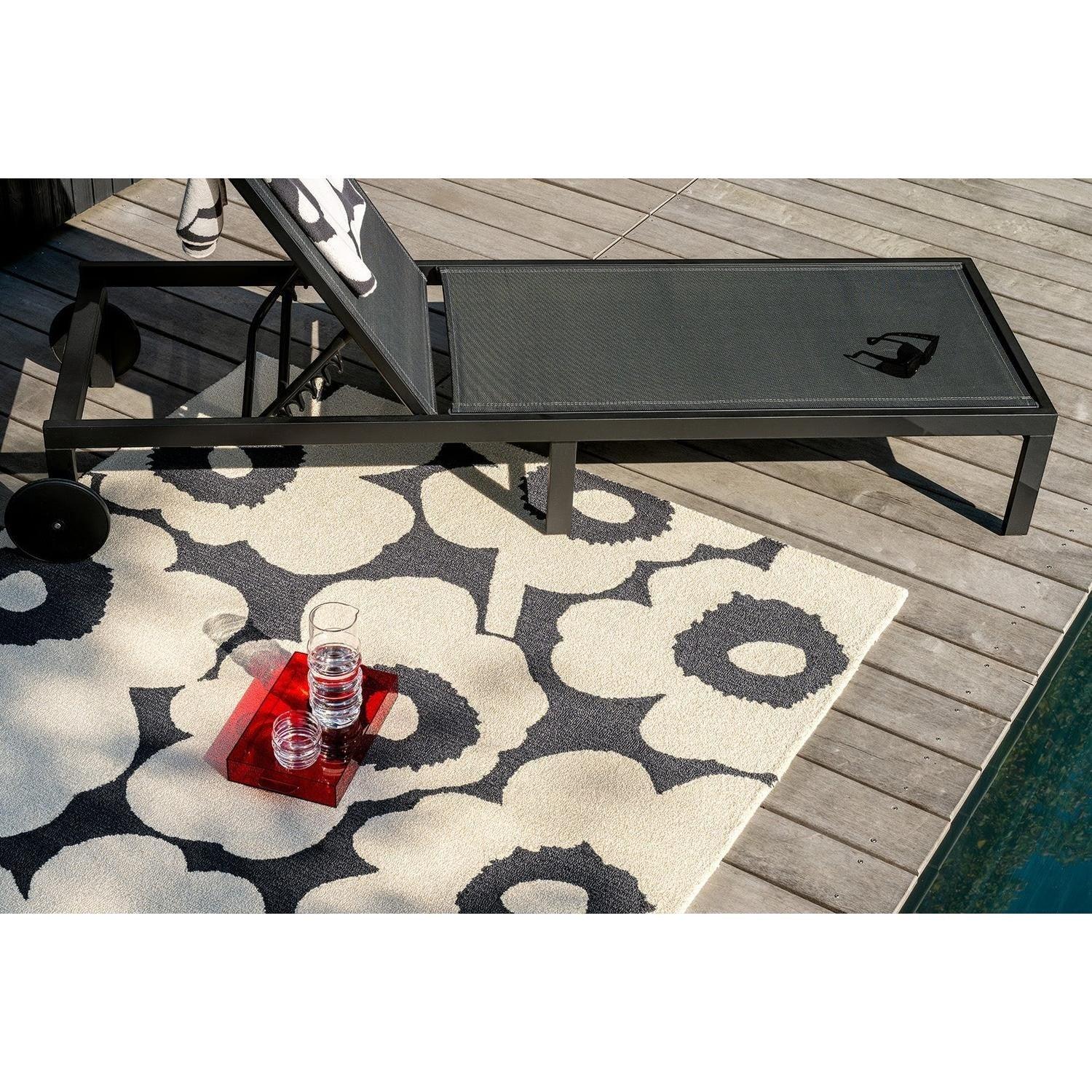 ICONIC RUGS Marimekko Unikko outdoor rug in charcoal and ivory. Features oversized poppy floral design, handtufted 100% recycled PET, 11mm pile.