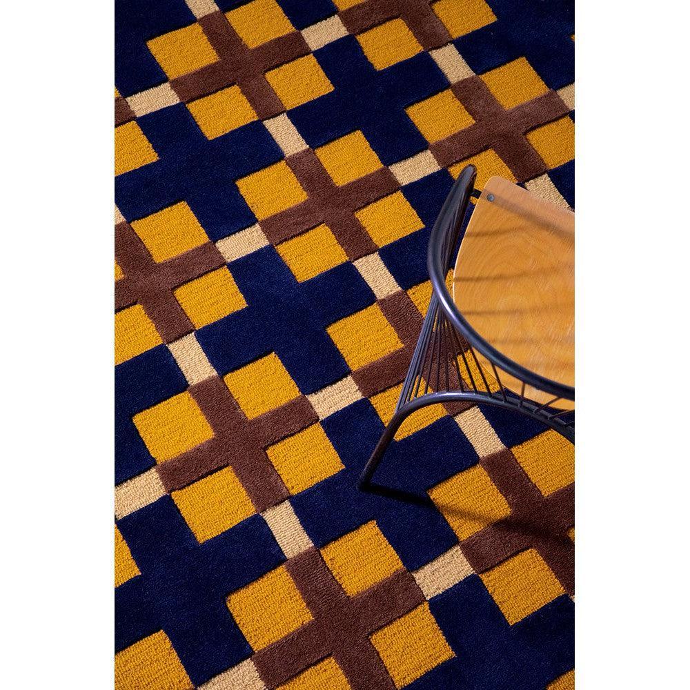 Brink & Campman Decor Milano Rug featuring geometric grid in ochre, navy and brown on dark blue, machine-woven wool