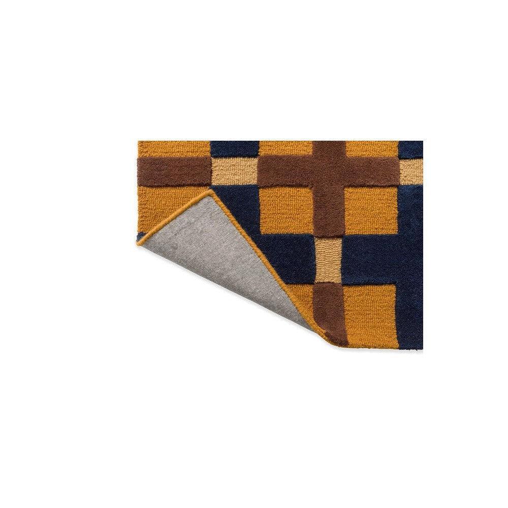Brink & Campman Decor Milano rug featuring geometric checker pattern in golden ochre, navy and brown on navy background, hand-tufted wool